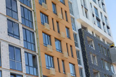 İnşaat halindeki çok katlı bir binanın dış duvarlarını yalıtma süreci. İnşaat konsepti.