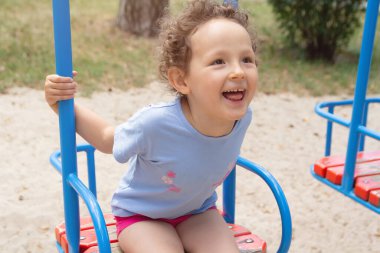 Kıvırcık çocuk yaz parkında salıncak için. İnsanlar