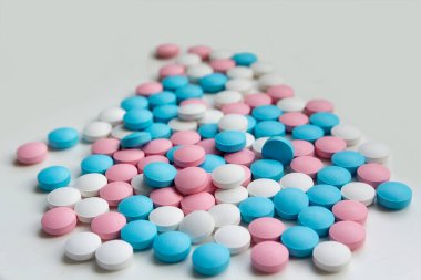 Masaya saçılmış beyaz, mavi ve pembe tabletler. Arkaplan