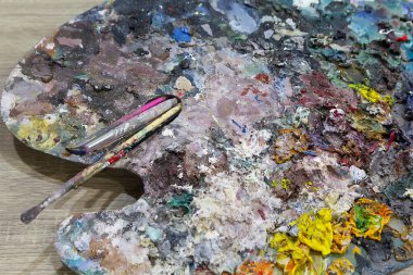 Renkli boya damlaları ve fırça ile canlı bir sanatçı paleti, yaratıcı projeler için mükemmel.
