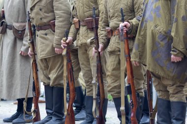İkinci Dünya Savaşı 'nın Sovyet piyadeleri gibi giyinmiş adamlar tüfekleri ellerinde tutuyorlar.