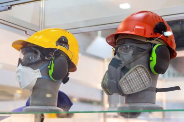 Kasklı mankenler, güvenlik gözlükleri, kulaklıklar ve sergi salonunda bir solunum cihazı. İşçi koruması