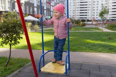 Evin yanındaki çocuk parkında salıncakta sallanan tatlı bir bebek. İnsanlar