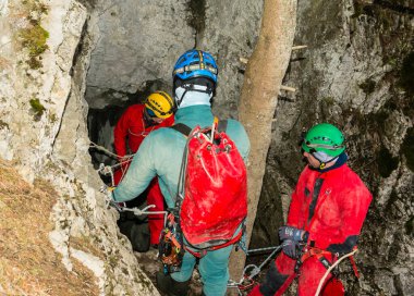 Koscielisko, Poland - March 03, 2024: A group of cavers in front of the entrance to the Czarna (Black) Cave in the Western Tatras. Poland. clipart