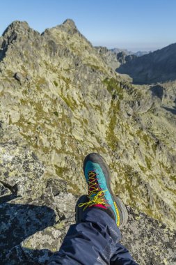 Strbske Pleso, Slovakia - August 29, 2024: A climber resting in the mountains wearing Mammut Eisfeld Light SO pants and La Sportiva TX4 R approach shoes. clipart