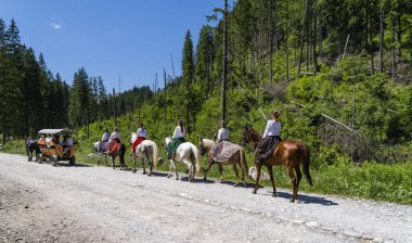 Tanık, Polonya - 22 Haziran 2025: Geleneksel İskoç (Podhale) kostümlü kadınlar, bayram ayini için vadideki şapele at binerek gidiyorlar..