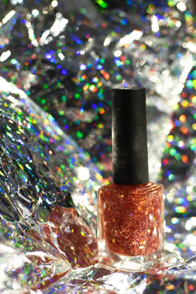 Orange nail paint with glitter mixed in. The back has a blurry bokeh light