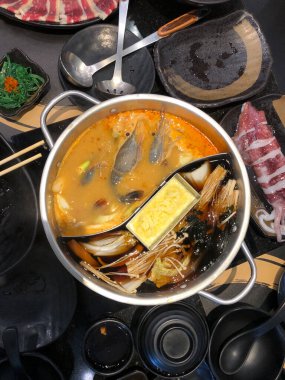 Shabu 'nun iki çeşit çorbası var, ortaya yerleştirilmiş, taze domuz eti, domuz eti, sığır eti ve nehir karidesleri de dahil olmak üzere pişmiş tabaklarla çevrili.