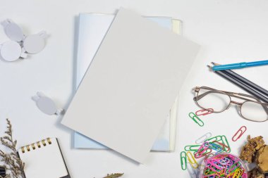 Çerçevenin ortasında beyaz bir arkaplana yerleştirilmiş okul malzemeleri varyasyonu metin için boş bir kitap var. Okula geri dönme konusunda.