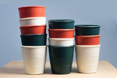 Çok renkli plastik saksılar, açık mavi çimento arka planında uzun bir şekilde üst üste dizilmişler.