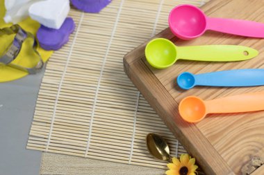 Plastik ölçü kaşığı ahşap tepsiye konmuş, pişirilmeye ya da tatlıya hazır.