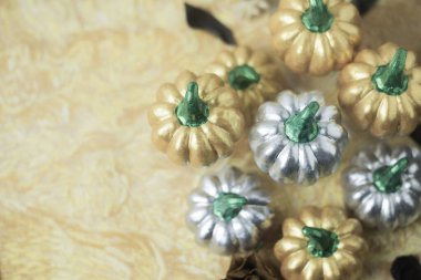 Alçıdan, gümüşten ve sarıdan yapılmış balkabakları. Sarı, pürüzlü bir arka plana yerleştirilmiş.