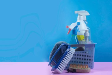 Temizlik ekipmanları ve araçları arkasında mavi bir arka plan ile pembe bir arka plana yerleştirilir.