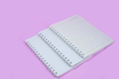 Pembe arka planda üst üste dizilmiş üç defter. Metne ve fikirlere girmek için boşluk var