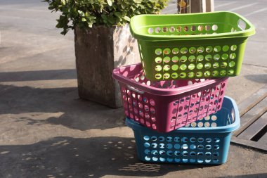 Üç parlak renkli plastik sepet birbiri ardına eski beton zemine konmuş.