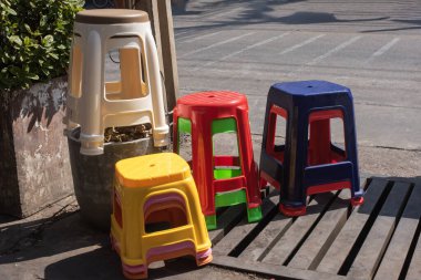 Plastik sandalye yol kenarına yığılmış birçok renk var. Düzensiz