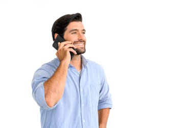 Mavi tişörtlü gülümseyen maço sakallı adamın portresi beyaz arka planda duran akıllı telefonu kullanıyor.