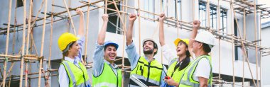 Group of contractors, engineers and formats in safety vests with helmets hands up to work together to successfully complete a construction project on construction site. cooperation and success concept