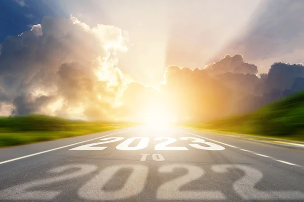 2023年の新年のコンセプトに移動します アスファルト道路上の日没や日の出光と空のアスファルト道路の真ん中に高速道路の道路に書かれた古い年の番号2022 — ストック写真