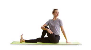 Genç ve güzel bir kadın, beyaz arka planda izole edilmiş yeşil yoga minderi üzerinde yoga dersi alıyor. sağlıklı yaşam tarzı kavramı