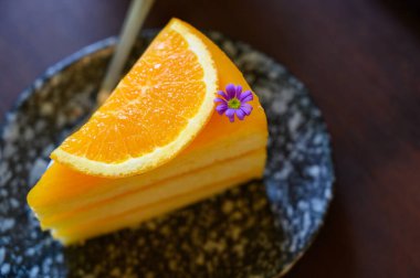 Bir dilim turuncu pasta ve kaşıkla dilimlenmiş portakal sosu. Fotokopi alanı olan turuncu kremalı kek