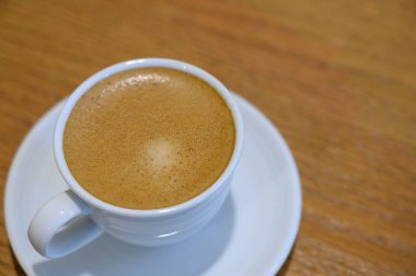 Sıcak kahve beyaz bardakta, ahşap masada, mutfak odasında, konforlu evde.