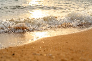 Deniz suyu yumuşak dalgası yaz aylarında gün batımında kumlu sahil kıyısına çarpıyor. yaz tatili etkinliği arka plan kavramı.