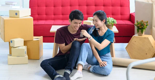Young Asian couple move into new apartment on Moving Day, celebrating moving to new home concept
