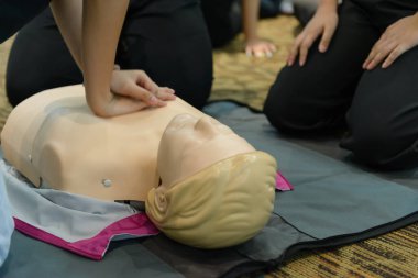 CPR First Aid Training with CPR dummy in the class. Demonstrating chest compressions concept
