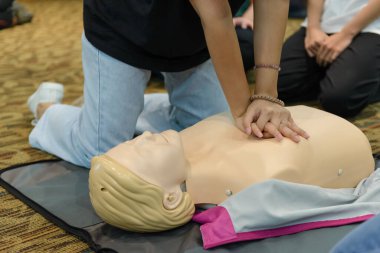 CPR First Aid Training with CPR dummy in the class. Demonstrating chest compressions concept