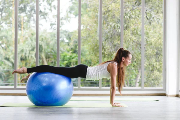 stock image Caucasian woman exercising with exercise ball. Fitness girls flexing abdominal muscles with fit ball in gym room