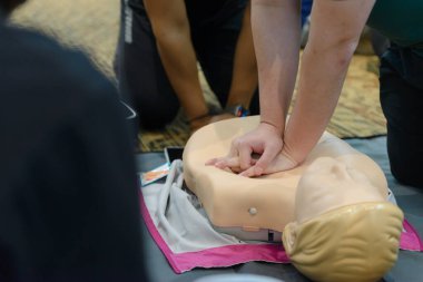 CPR First Aid Training with CPR dummy in the class. Demonstrating chest compressions concept