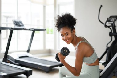 Sporty fitness African American woman working out with dumbbells strength and strength endurance at the gym