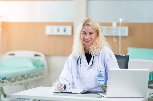 stock image A professional female doctor in white medical coat is working on her table in the patient room. Health care Concept