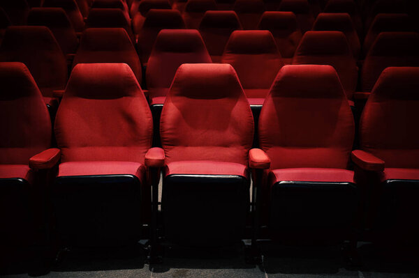 Interiors of empty comfortable red cinema chairs. Low-key. Dark tone