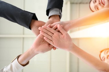 Happy united business team joins hands as a sign of business teamwork. stacking hands celebrating victory in office. concept of business success. low angle view clipart
