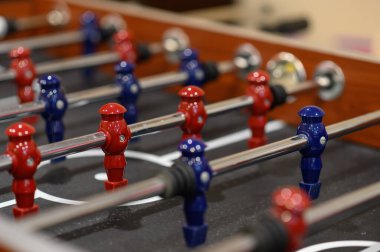 Eğlence merkezindeki masa futbolunda yakın plan plastik oyuncular. Kırmızı ve mavi oyunculu futbol masası