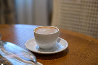 Sıcak kahve beyaz bardakta, ahşap masada, mutfak odasında, konforlu evde.