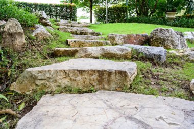 Dev taş, bahçeyi birbirine bağlayan merdivenlere çıkıyor.