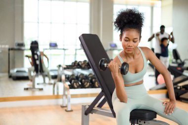 Sporty fitness African American woman working out with dumbbells strength and strength endurance at the gym