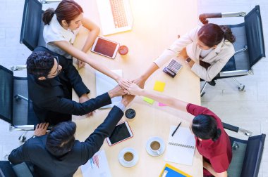 İş adamlarının masanın üzerinde el çırpışları, masanın altına yerleştirilmiş grafikler. Genç işadamı ve iş kadını el birliği ve takım çalışması desteği gösteriyor.