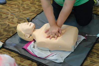CPR First Aid Training with CPR dummy in the class. Demonstrating chest compressions concept