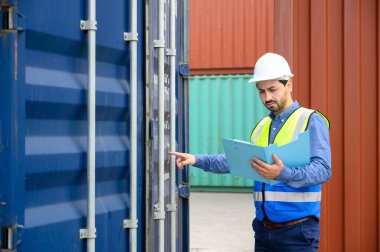 Foreman ya da Mühendis, konteynır kutusunun envanter detaylarını kontrol etmek ya da kontrol etmek için beyaz kask ve yansıtma gömleği giyer. Ticari lojistik sektörünün ithalat ve ihracatında kargo taşımacılığı yapan konteyner