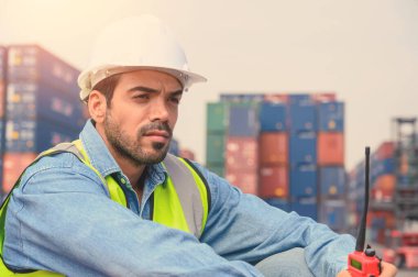 Portrait of Container operator holding walkie talkie at Container cargo site checkup goods in container. import export shipping business concept