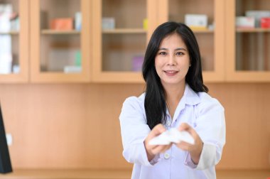 Eczanede tezgahta duran kadın eczacının gülümseyen portresi. Kameraya bakıyorum.