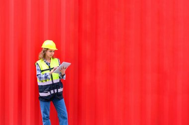 Engineer women wear yellow helmets and reflection shirts working on tablet computers to check inventory details of containers box. Inspector or Safety Supervisor in Container Terminal