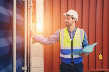 Foreman ya da Mühendis, konteynır kutusunun envanter detaylarını kontrol etmek ya da kontrol etmek için beyaz kask ve yansıtma gömleği giyer. Ticari lojistik sektörünün ithalat ve ihracatında kargo taşımacılığı yapan konteyner