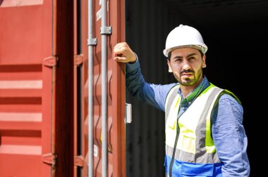 Konteynır lojistik işçileri sarı kasklar ve yansıtma gömlekleri giyiyorlar ve konteynırları denetlemek ve depo konteynerindeki konteynırların durumunu kontrol etmek için açık konteynırlar kullanıyorlar. lojistik sektörü ihracat endüstrisi