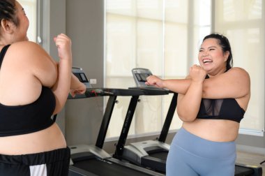 Kilolu Asyalı kadın spor salonundaki ana egzersizlerden önce geriniyor. Kilo verme egzersizi, sağlıklı yaşam tarzı konsepti