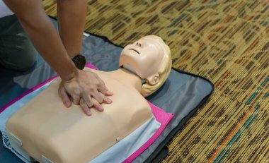 CPR First Aid Training with CPR dummy in the class. Demonstrating chest compressions concept